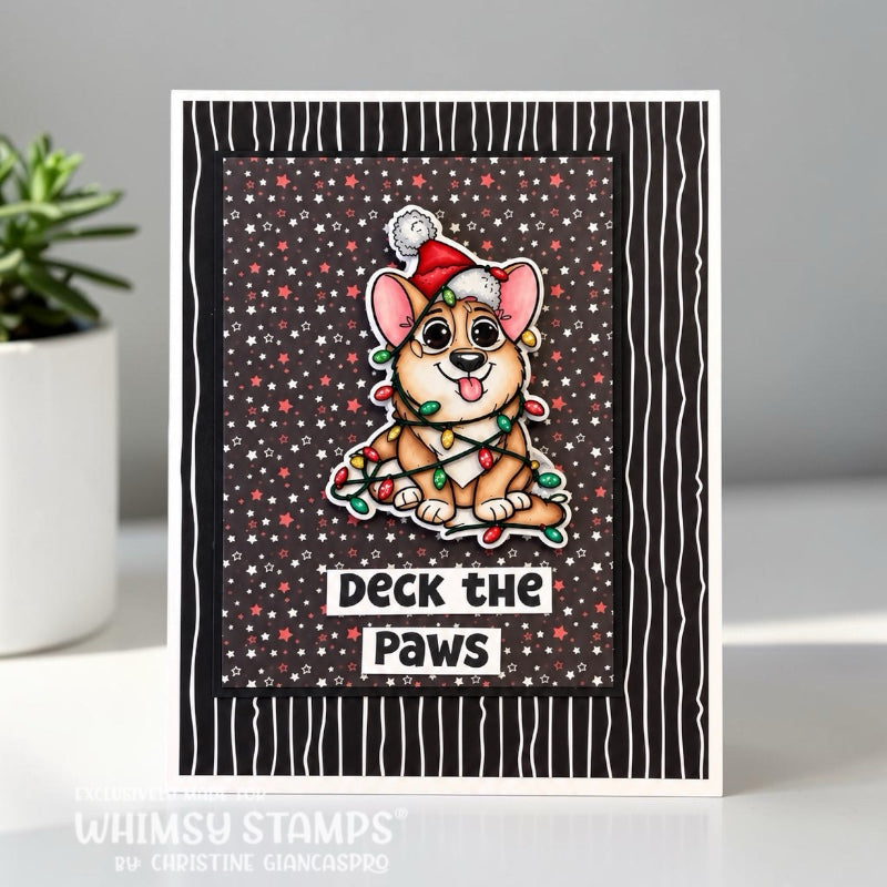 A handmade greeting card featuring a cute cartoon dog wearing a Santa hat and holiday lights, with the text 'DECK THE PAWS' on a black and white striped card. 