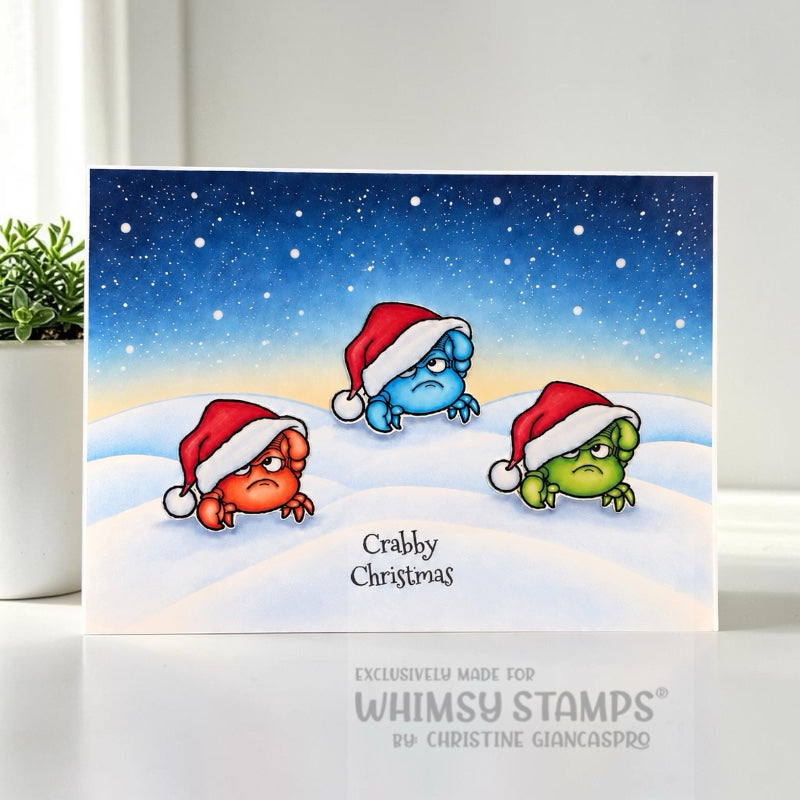 A handmade greeting card featuring three cartoon crabs wearing red and white Santa hats in a snowy winter scene under a starry night sky. Sentiment says Crabby Christmas.