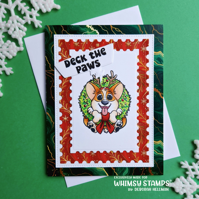 A handmade Christmas greeting card featuring a cartoon dog wearing a green wreath and reindeer antlers, with the text 'Deck the Paws' on a white tag. 