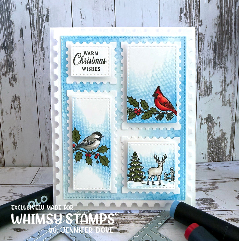 A handmade Christmas card with four postage-stamp-style panels, featuring a cardinal, chickadee, holly, deer, and snowy tree, with the text 'Warm Christmas Wishes.' 