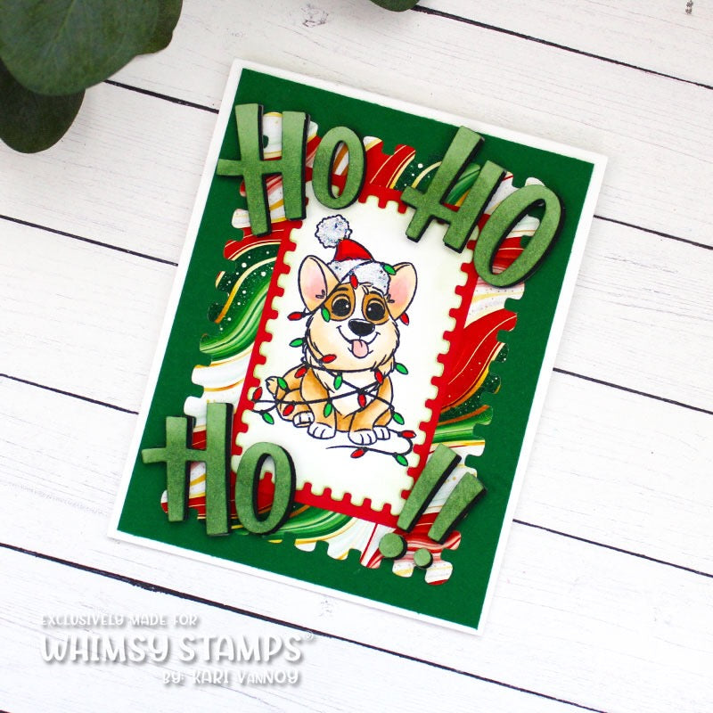 A handmade Christmas greeting card featuring a cartoon Corgi with a Santa hat and Christmas lights, surrounded by green 3D letters spelling 'Ho Ho Ho' and red and green designer paper details, displayed on a white wood background.