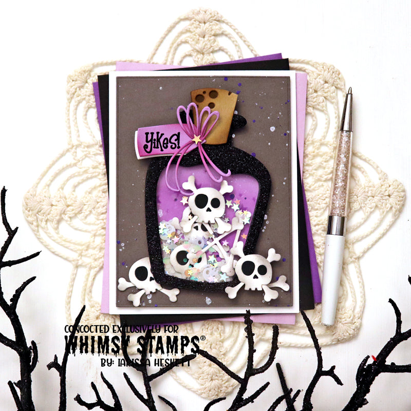 A handmade gothic-themed card featuring a black glitter potion bottle filled with white skulls and purple confetti, with a purple 'Yikes!' tag. 