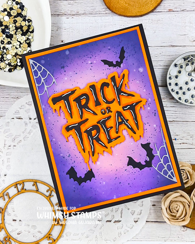 A handmade Halloween card with 'Trick or Treat' in orange and black 3D lettering over a purple gradient background with bats, spiders, and spiderwebs. 