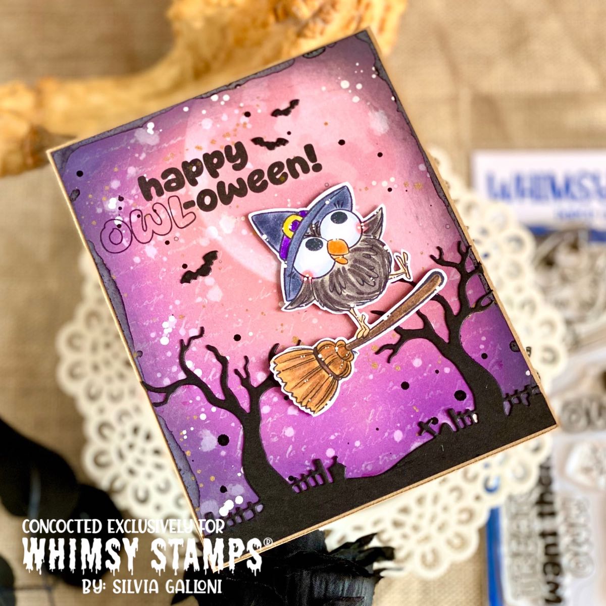 A handmade Halloween card featuring a cartoon owl on a broomstick against a pink and purple sky, with black trees and the text 'happy OWL-oween!'. 